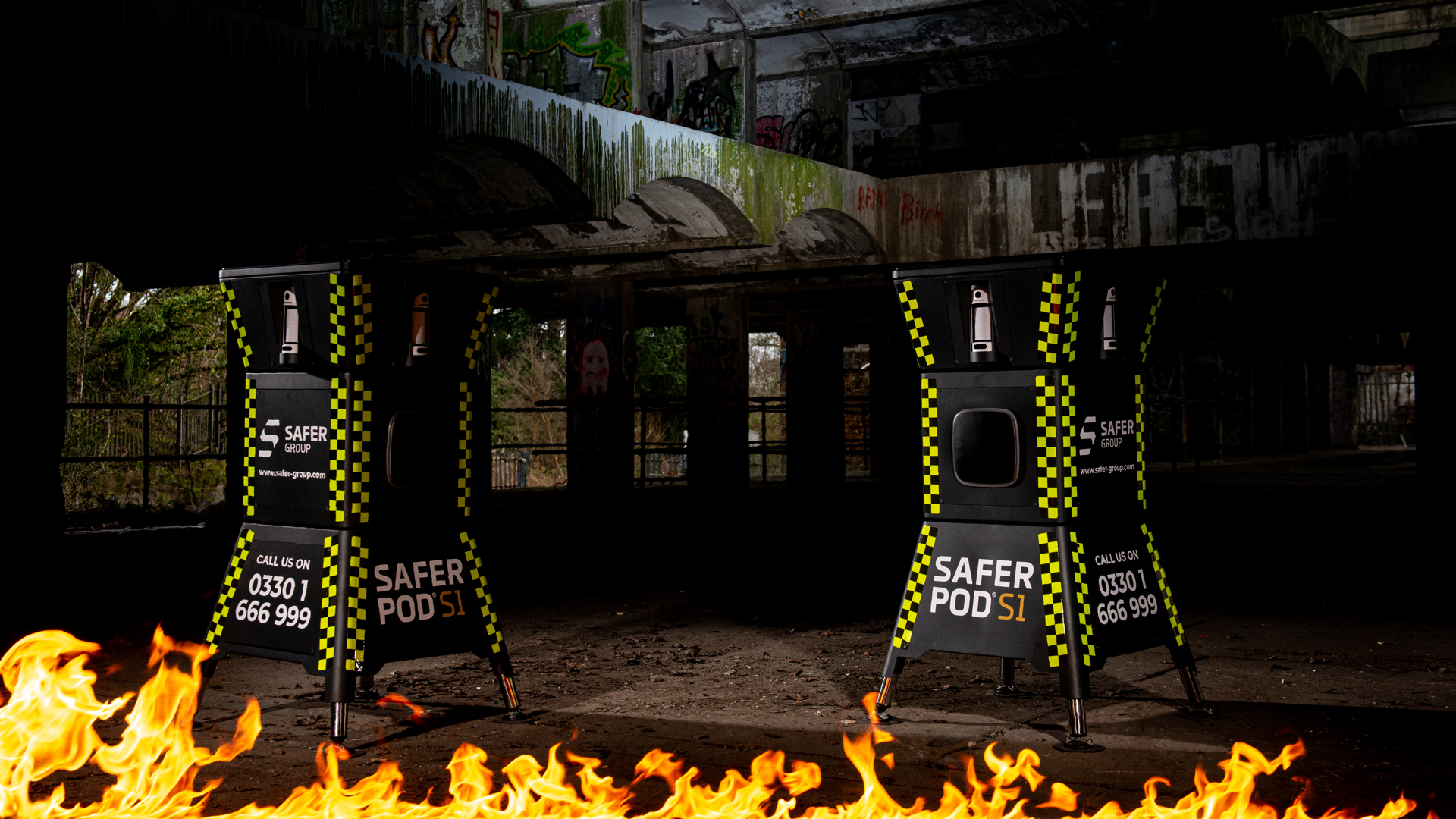 two safer pod s1 devices stand in a dark underground setting, with a strip of fire illuminating the scene.