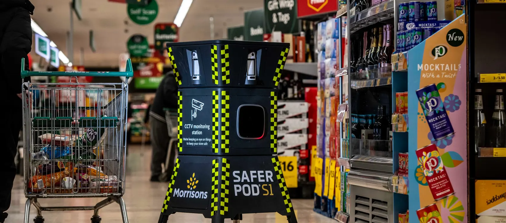 A Safer Pod S1 stands in a morrisons supermarket aisle next to a shopping cart filled with groceries.