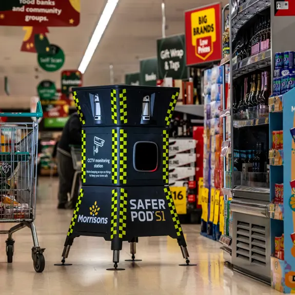 A Safer Pod S1 stands in a morrisons supermarket aisle next to a shopping cart filled with groceries.
