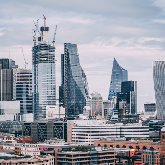 landscape of a modern busy city on a cloudy day, with old and modern architecture combined between large glass structures and older brick buildings